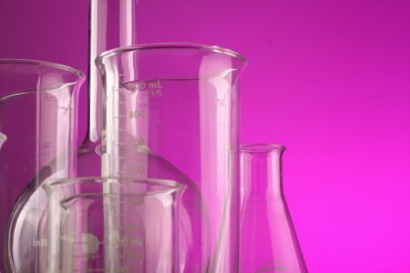 Bêcher, erlenmeyer, ballon en verre : matériel de chimiste. Sur fond rose