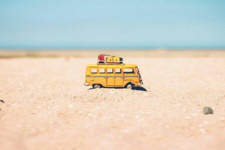 Un jouet mini bus avec bagages sur le toit sur la plage