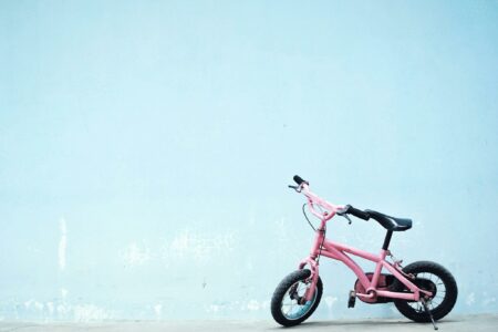 Une petite draisienne rose devant un mur bleu