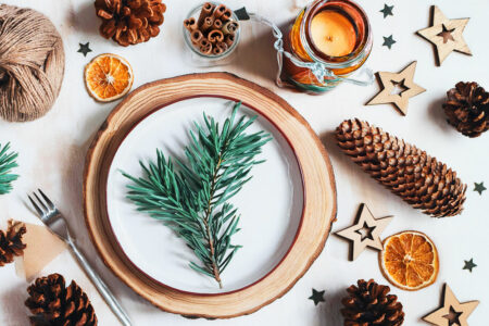 Une table festive de Nouvel an décoré de manière écolo avec des éléments naturels comme des pommes de pin, des branches de sapin ou des bougies artisanales