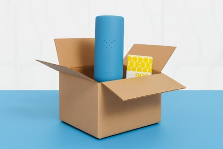 Un carton de livraison ouvert, avec un gel douche 900.care qui dépasse du carton